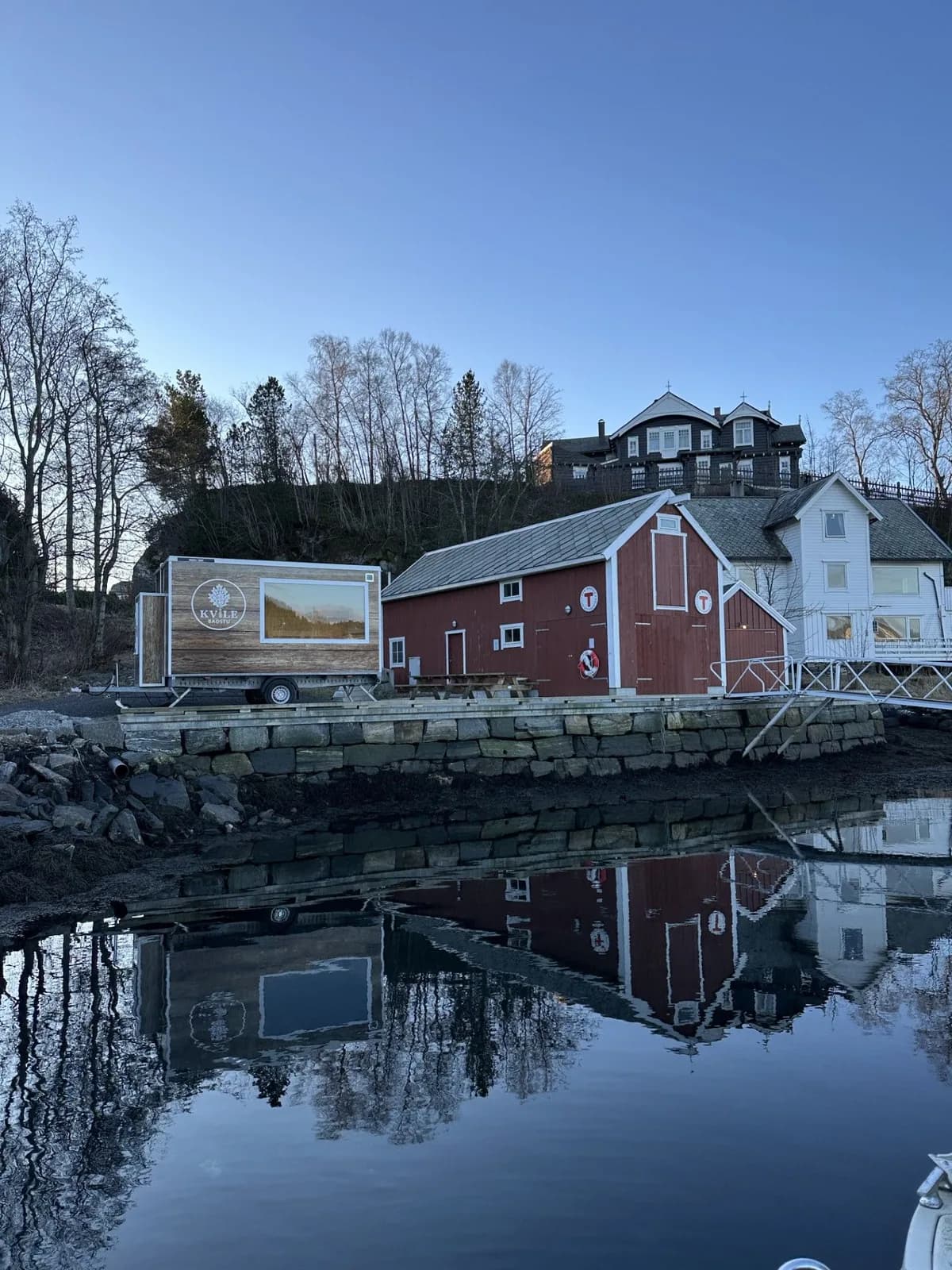 Kvile Badstu mobil badstu ved sjøen i Ålesund, med raudt naust i bakgrunnen