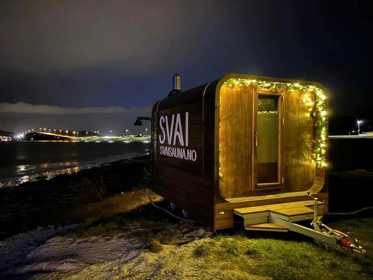 Svai Sauna Kubben mobil badstue ved sjøen om kvelden i Ålesund med julelys