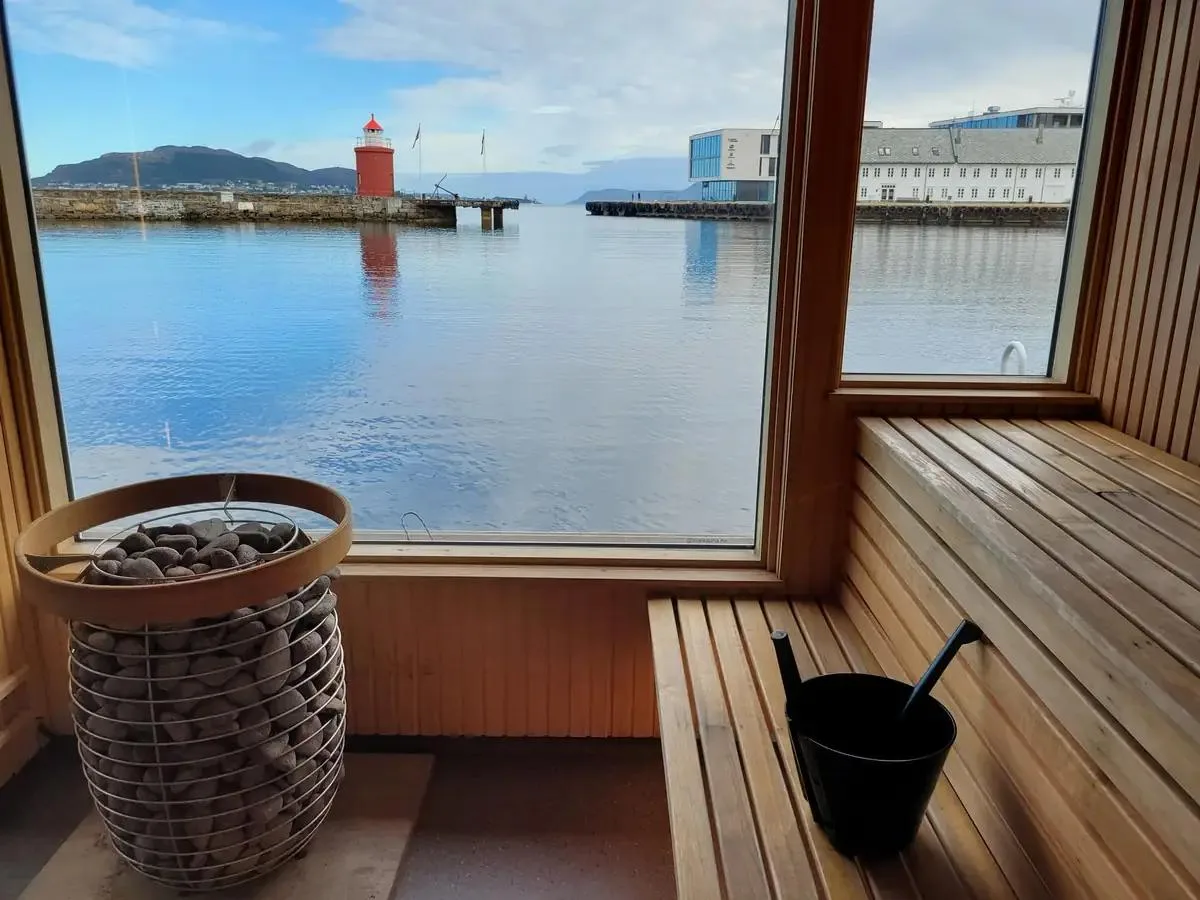 Interiør i Svai Sauna Molja i Ålesund med saunaovn og utsikt over havnen og Molja fyr