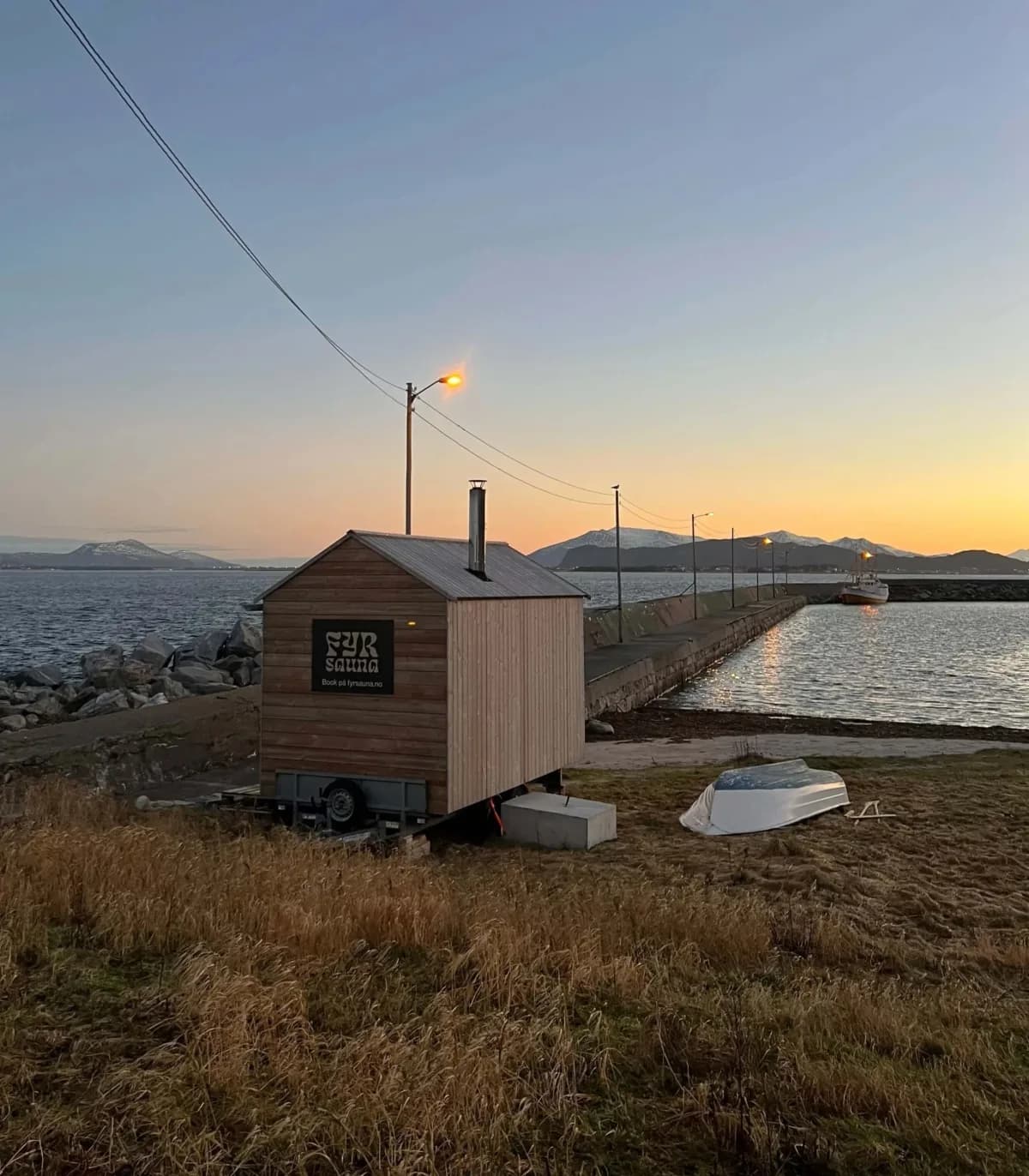 Fyr Sauna i Alnes, mobil badstue ved sjøen i solnedgang med fjell i bakgrunnen