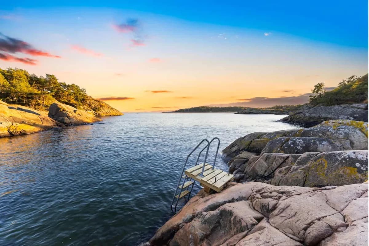 Solnedgang over sjøen ved Sandaa Badstue i Arendal med badestige i svaberget