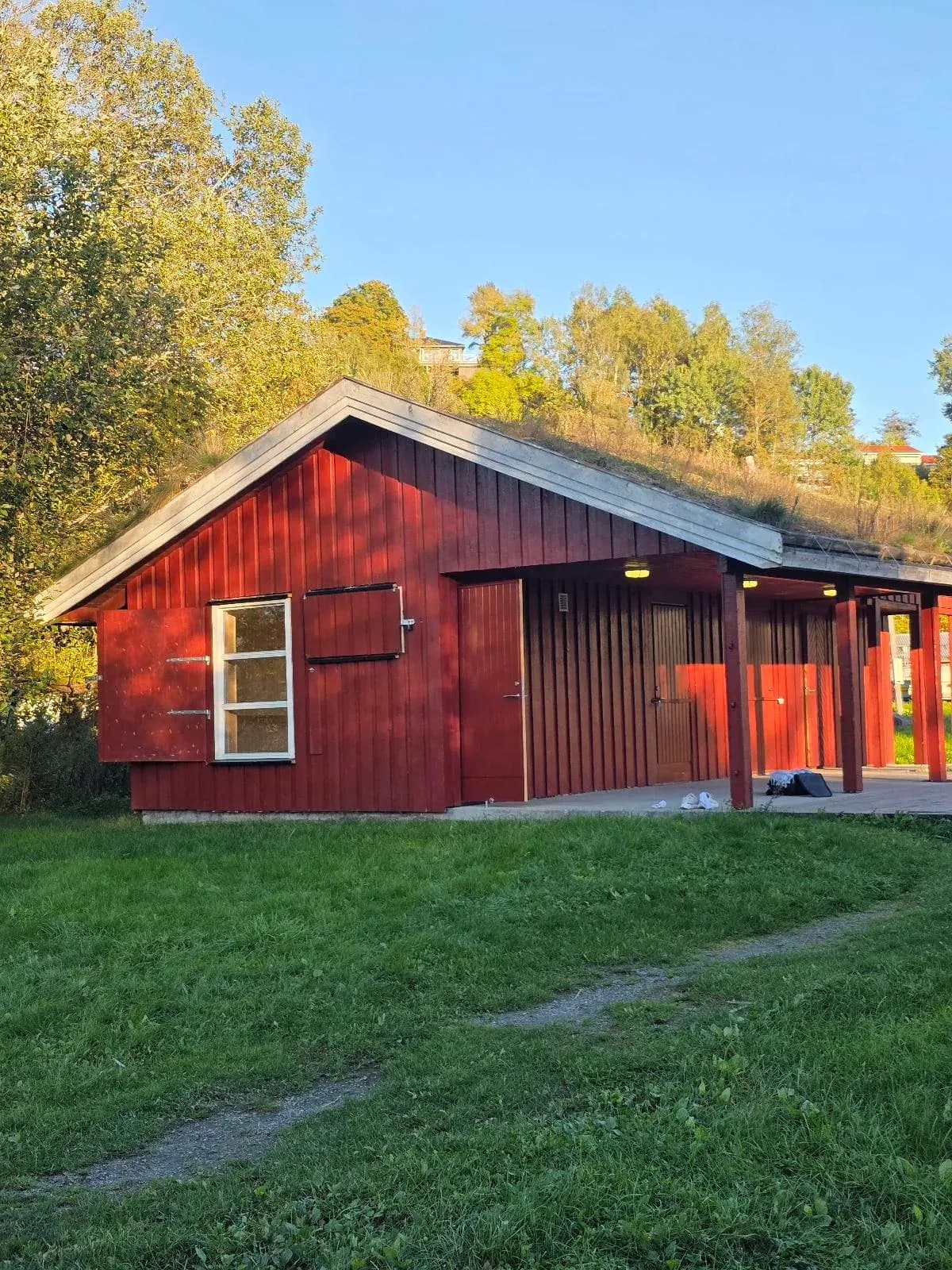 Rødt badstubygg med torvtak ved Gjellumvannet, Vinterlykke Badstue i Asker
