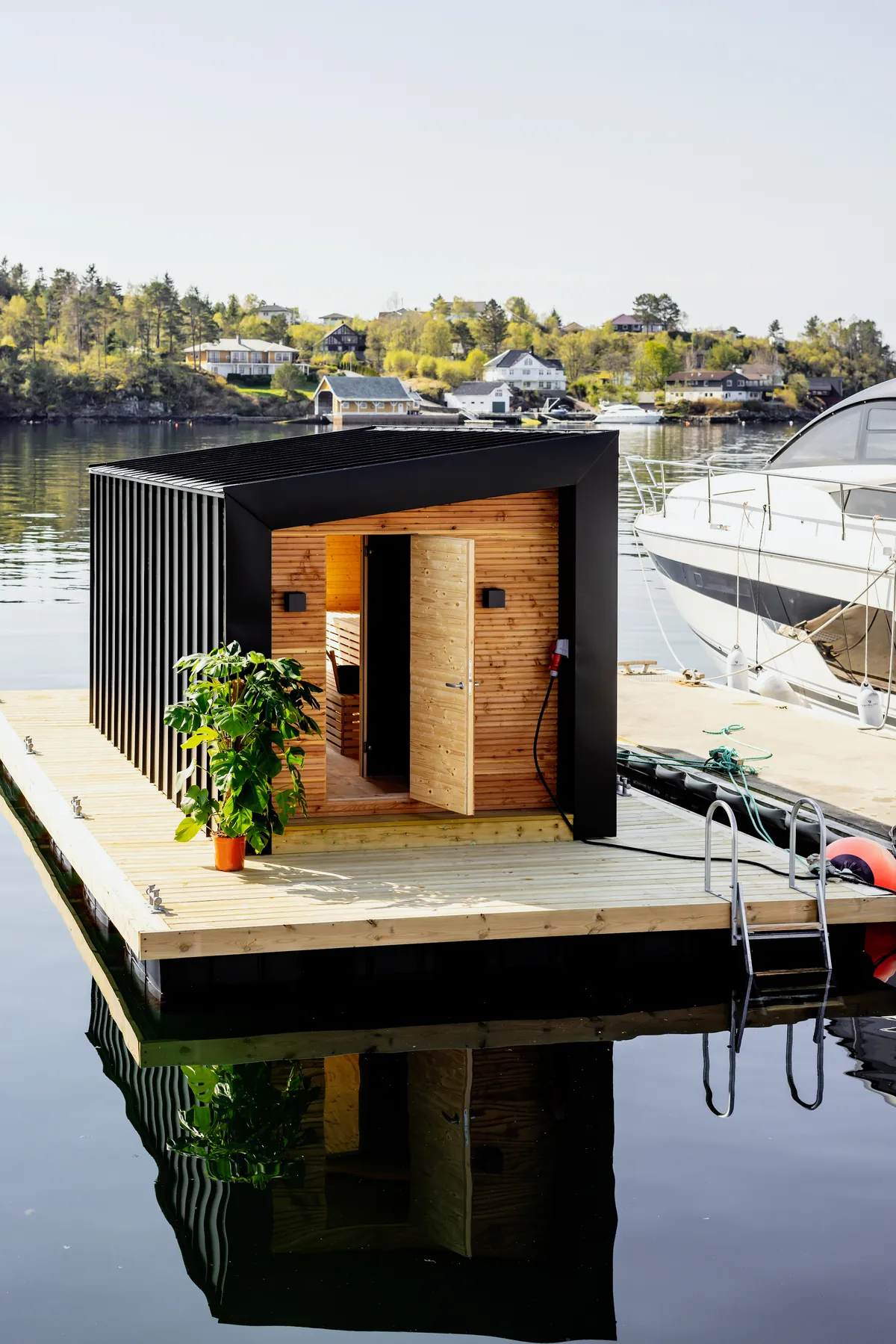 HAVN Sauna – eksterior Badstuebygget på brygga ved HAVN Hjellestad, med båter fortøyd ved siden av og badestige ned i sjøen