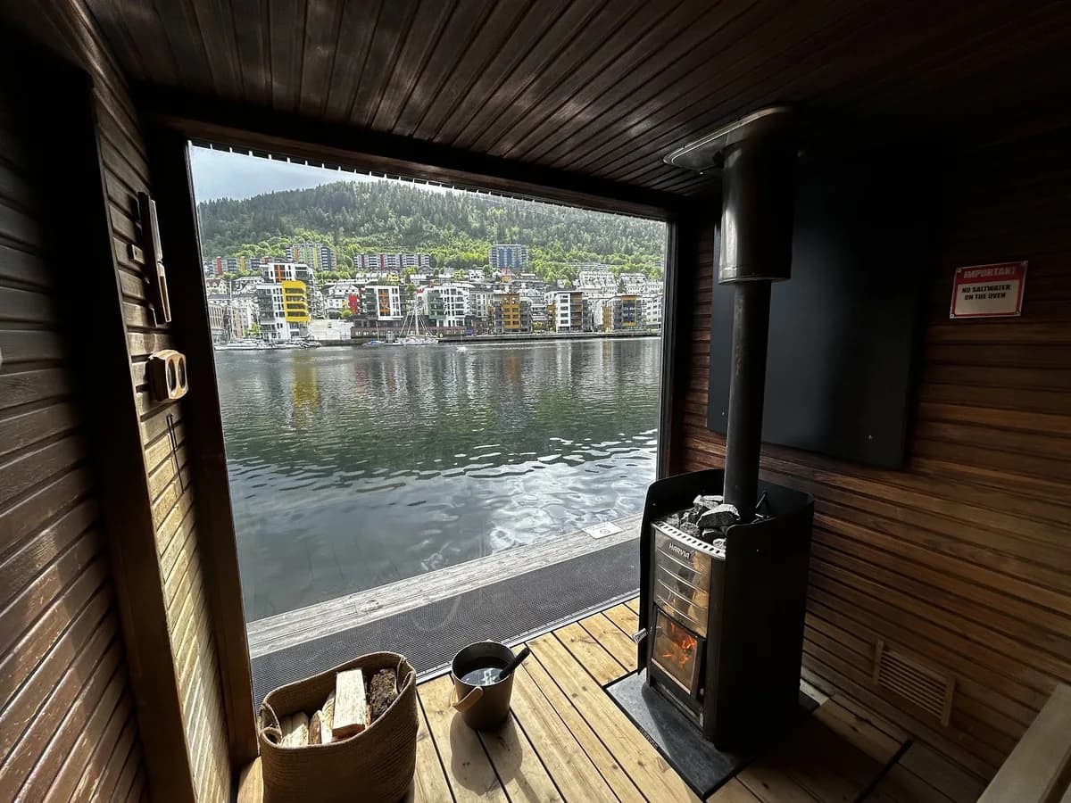 Interiør av Heit Bergen Marineholmen flytende badstue med vedfyrt ovn og utsikt over Bergen by og sjøen