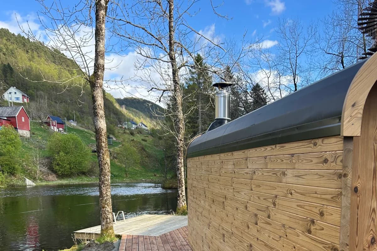 Osterøy Badstue ved elvebredden med grønne åser i bakgrunnen, Bergen