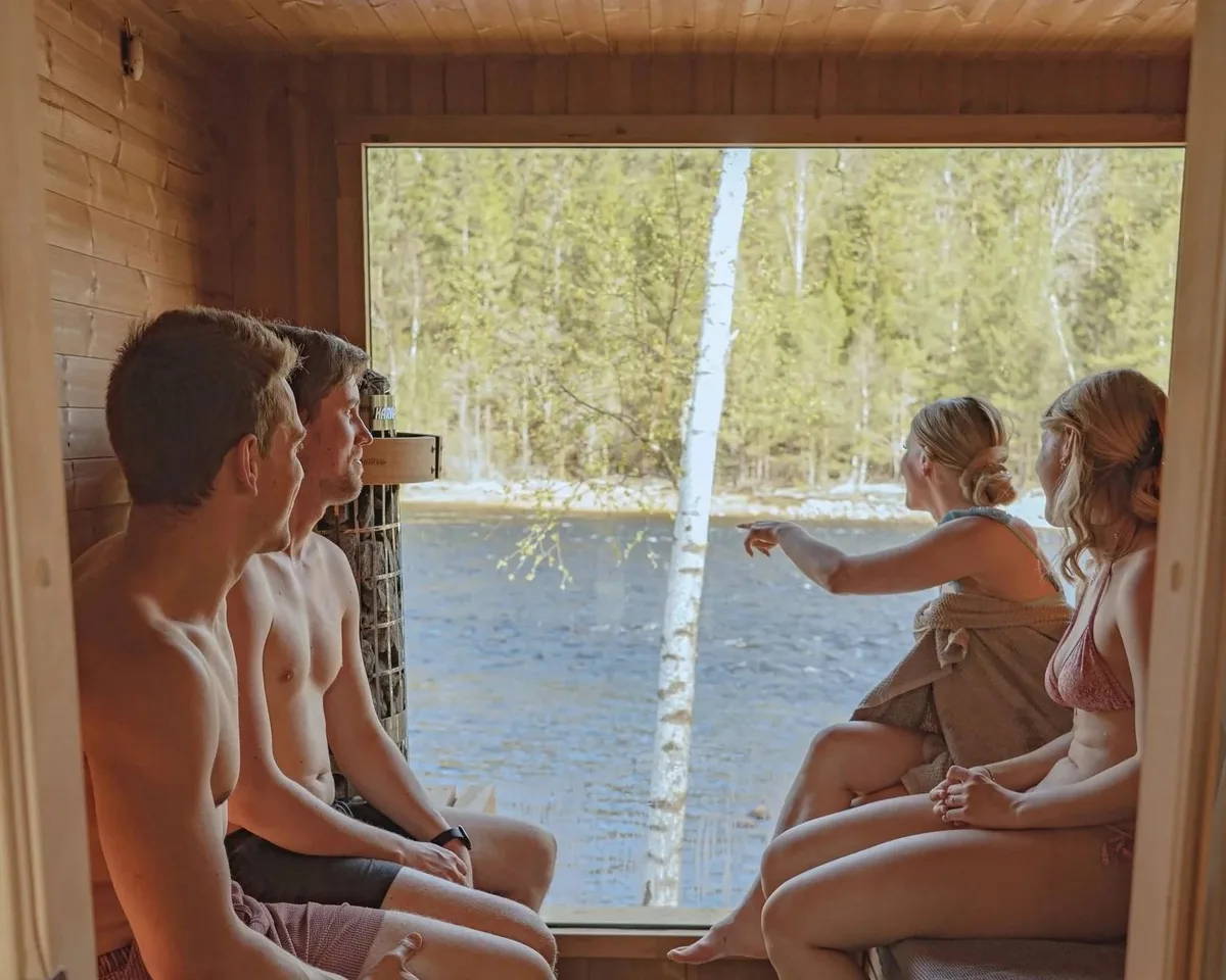 Mennesker nyter badstuen Elvestua i Birkeland med utsikt mot elven