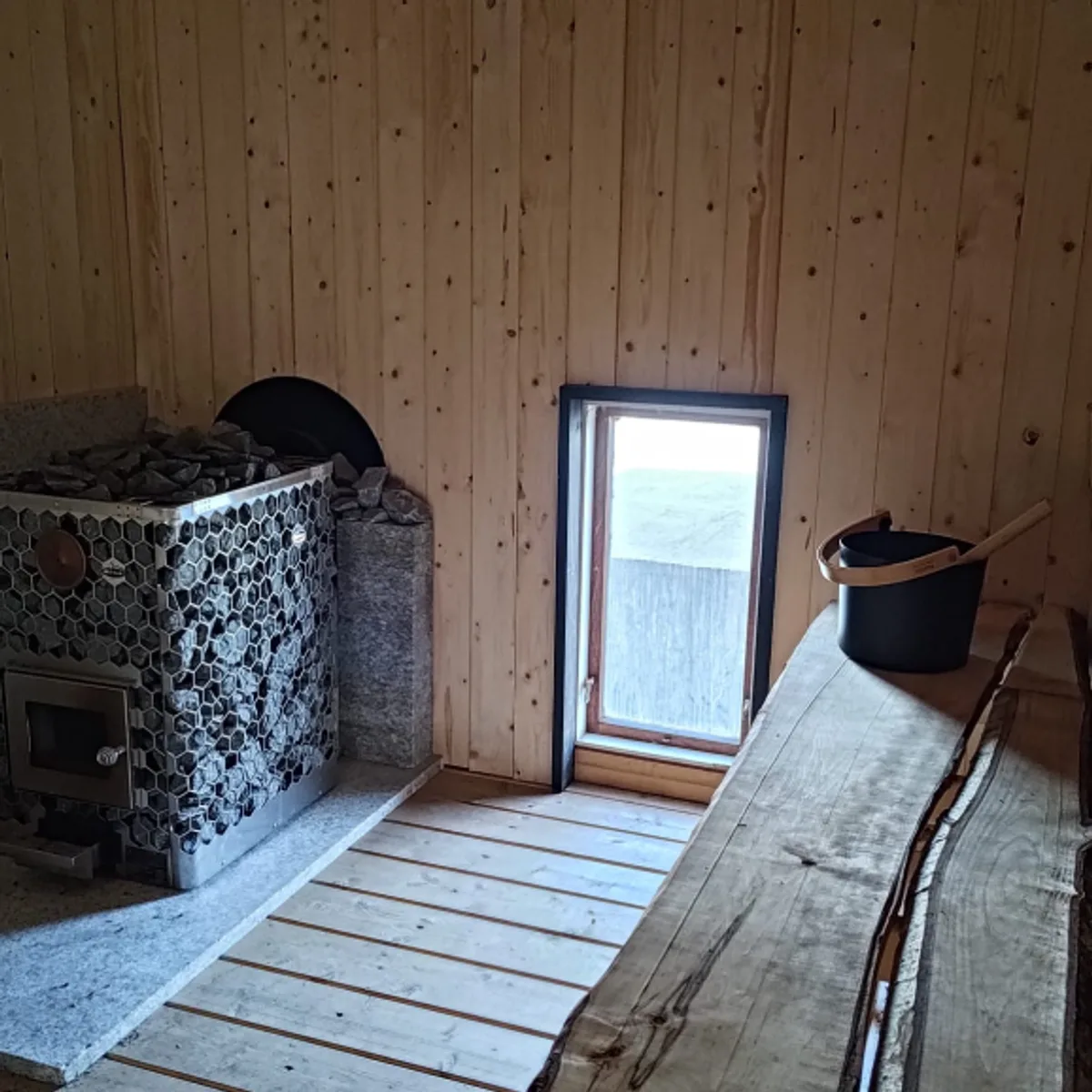 Vedfyrt badstueovn med steinmur inne i Nordnorsk Badstuforening i Bodø