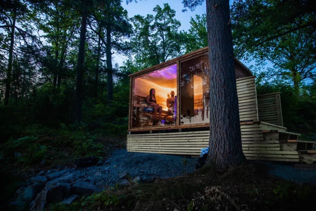 Aurora Sauna i Eidsfoss opplyst om kvelden, omgitt av skog ved Eikern