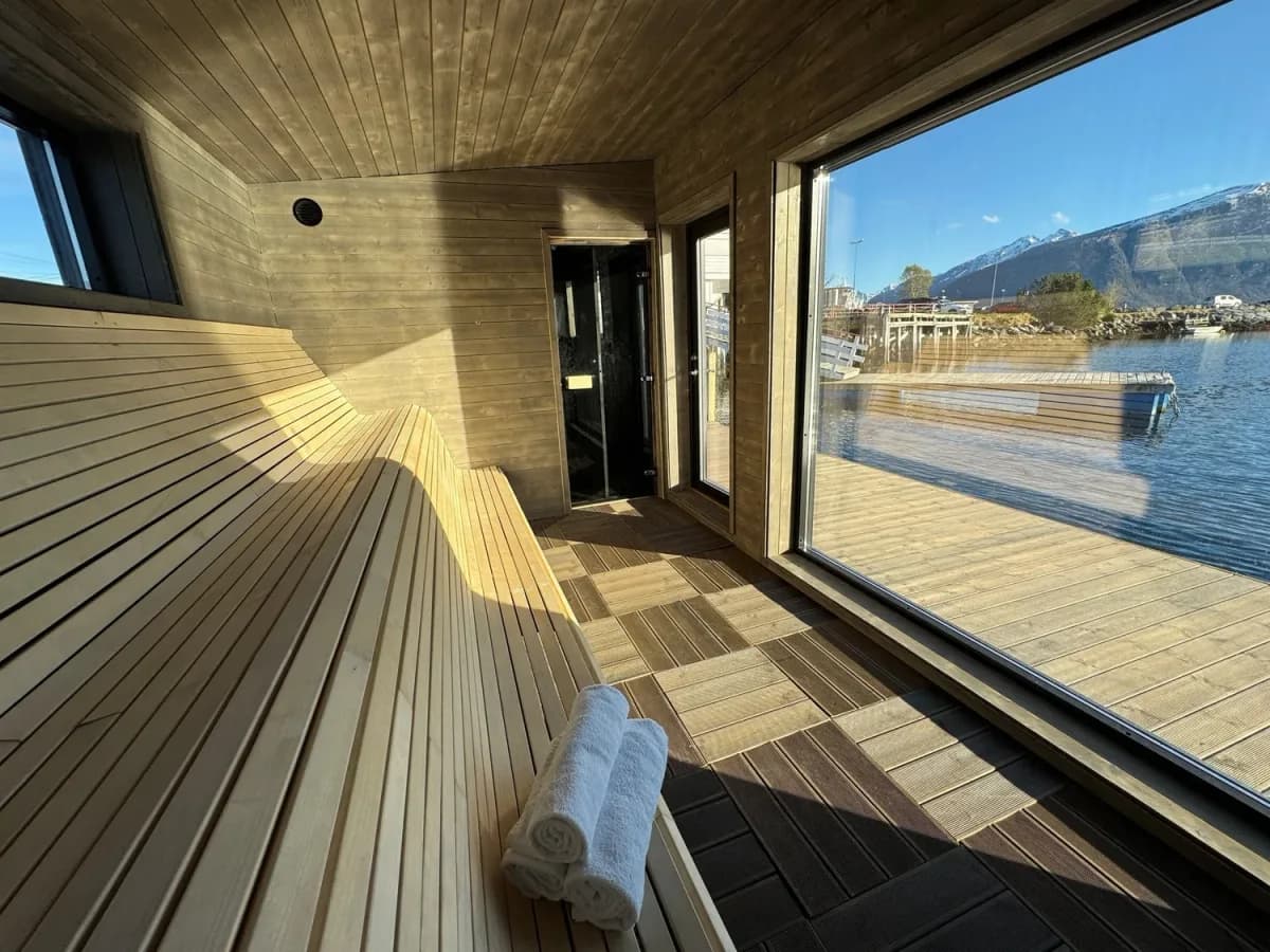 Interiør i Heit Sunde Sauna med trebenker og panoramautsikt mot fjorden i Eidsnes