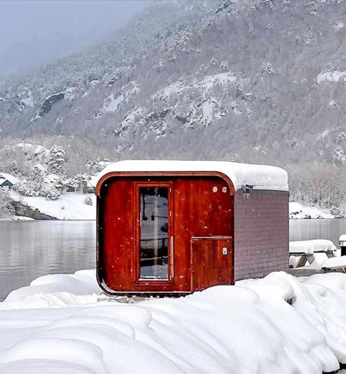 Fjelg Sauna i vinterlandskap, Eikefjord Fjelg Sauna ved sjøkanten i Eikefjord, rød badstue i snølandskap med fjord og fjell