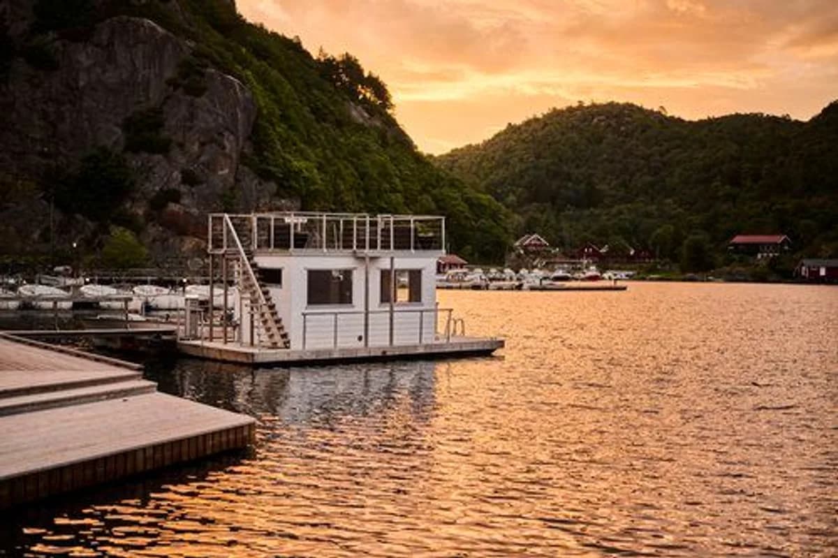 Flytende badstueflåte ved Farsund Resort i solnedgang med fjell i bakgrunnen