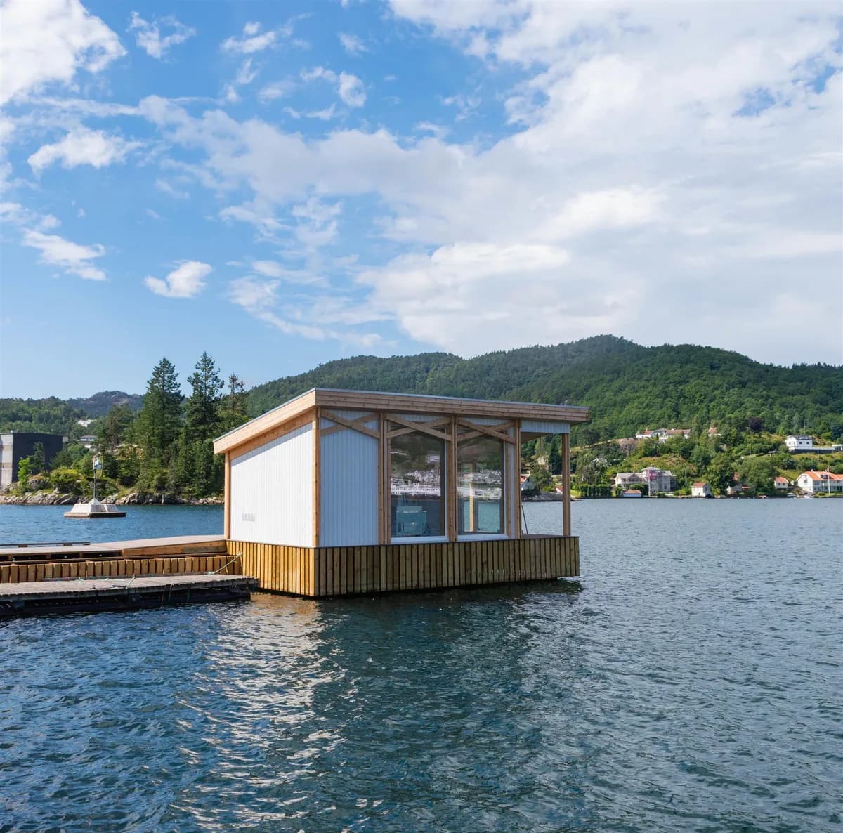 Grønnes Sjøbad badstue på brygge ved fjorden i Flekkefjord, med fjell og sjø i bakgrunnen