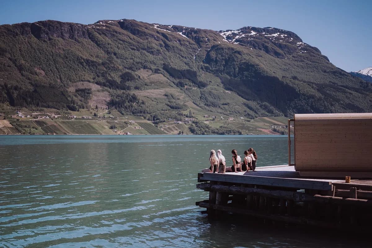 Heit Grimo Sauna ved Sørfjorden i Hardanger med gjester på brygga og fjordutsikt