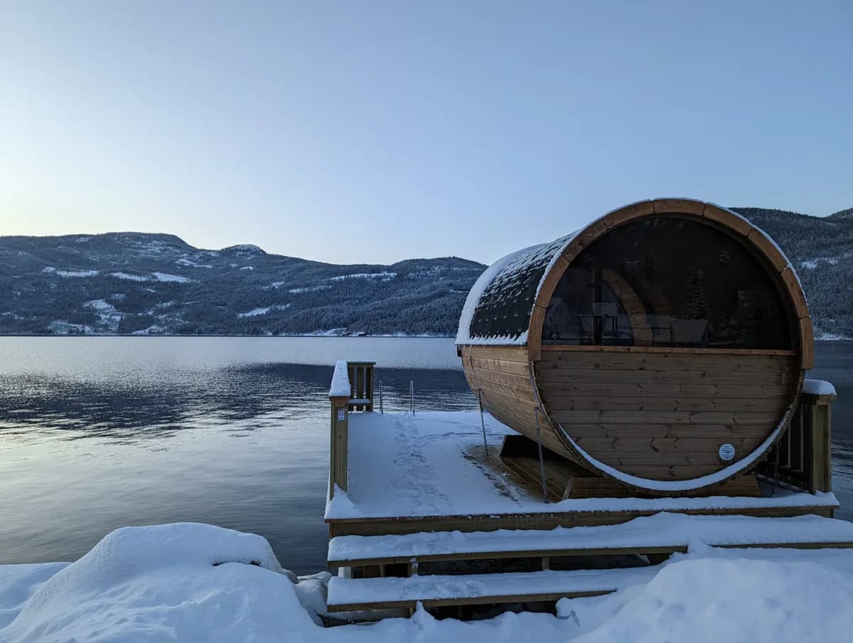 Tønnebadstu ved Bandak i Lårdal om vinteren med snødekt brygge og fjell i bakgrunnen