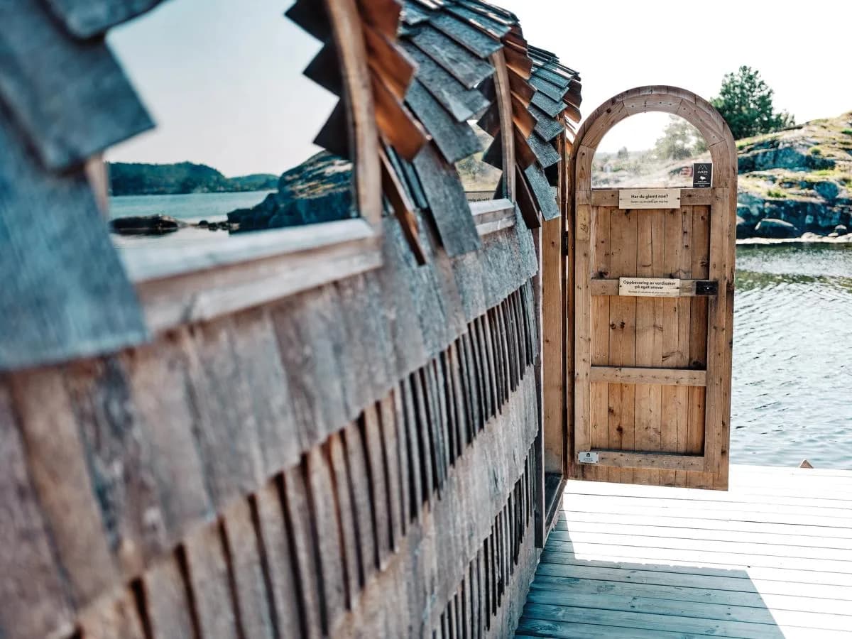 Oterøysauna i Kragerø skjærgård, trebygget badstu med bueformet dør ved sjøen