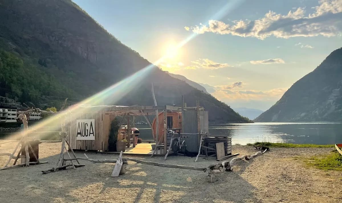 AUGA Sauna & Badehus i Lærdal sett utenfra med fjord og fjell i bakgrunnen ved solnedgang