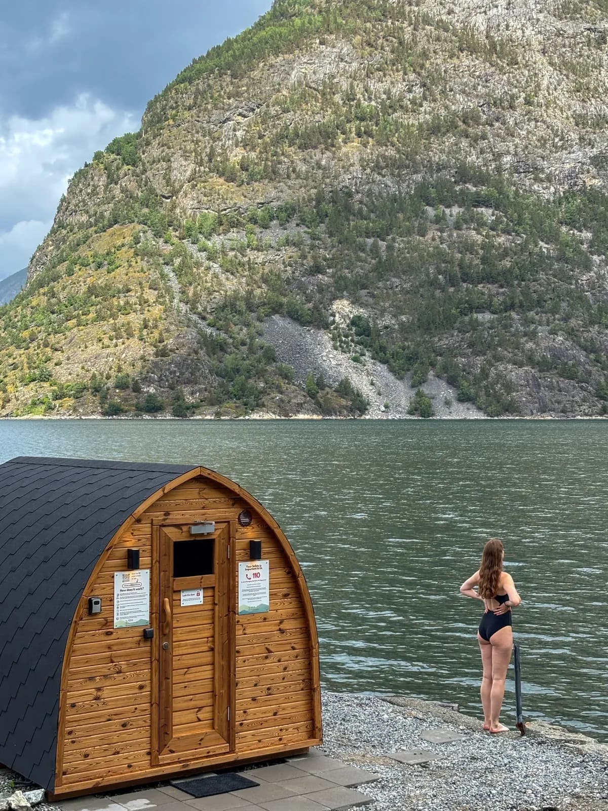 Badstuehytte ved fjorden med badegjest på svaberget ved siden av
