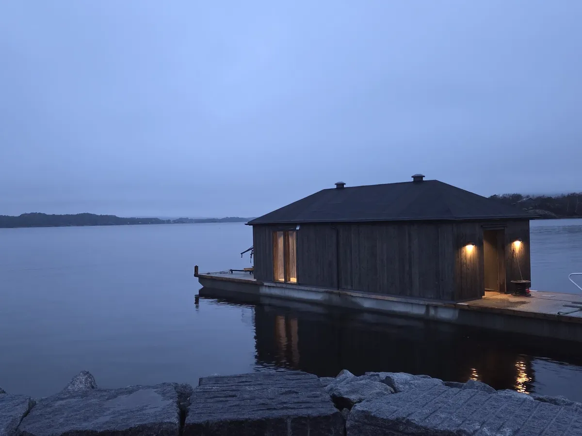 Helgeroa Badstue flytende badstue i Helgeroa havn ved kveldstid med varmt lys fra vinduene