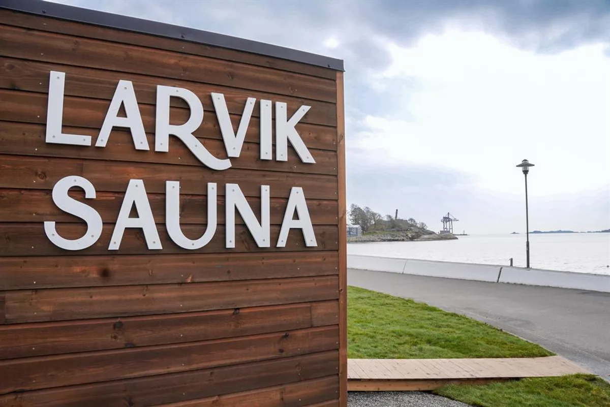 Larvik Sauna-skiltet i mørkt tre med fjordutsikt i bakgrunnen, Larvik