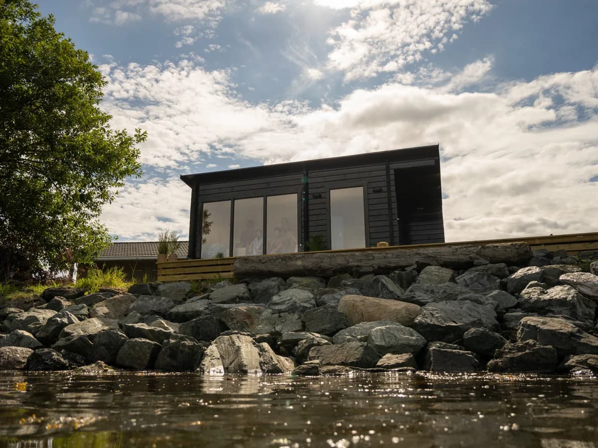 Stim Sauna i Levanger sett fra sjøen, moderne mørk bygning på steinbrygge