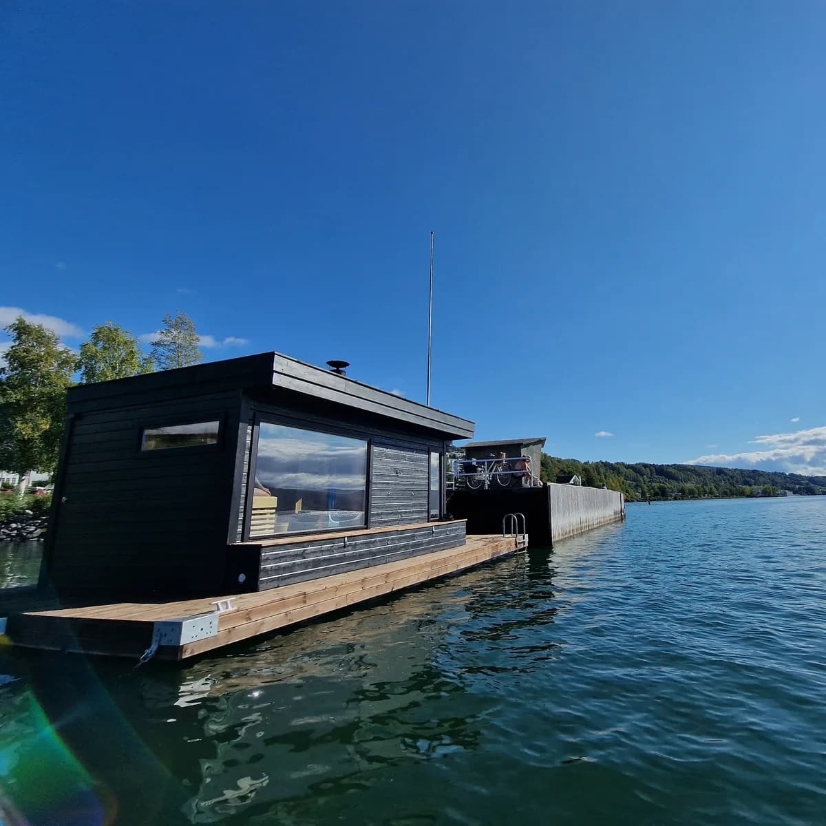 Badstufergen flytende badstue på Mjøsa i Lillehammer, sett fra vannet en sommerdag