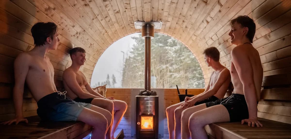 Interiør i vedfyrt tønnebastu hos Kroken Sauna i Lillehammer med utsikt mot snødekt skog
