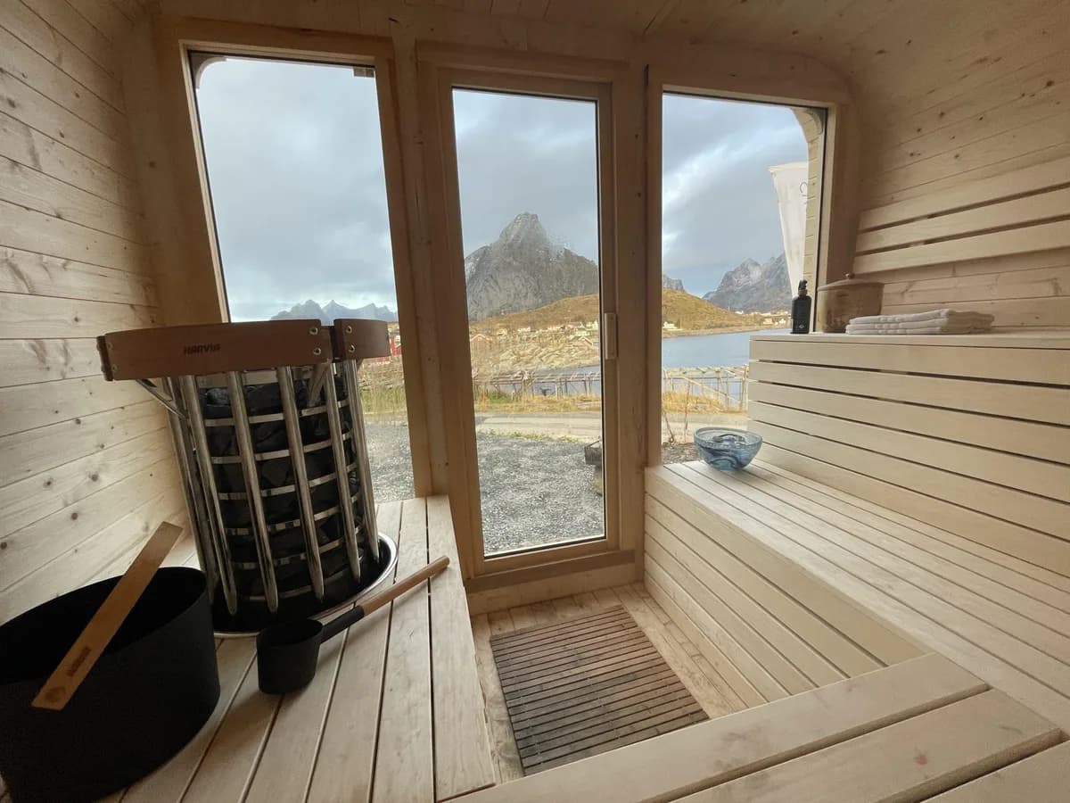 Interiør av Catogården Reine Sauna med elektrisk ovn og panoramautsikt over fjell i Lofoten