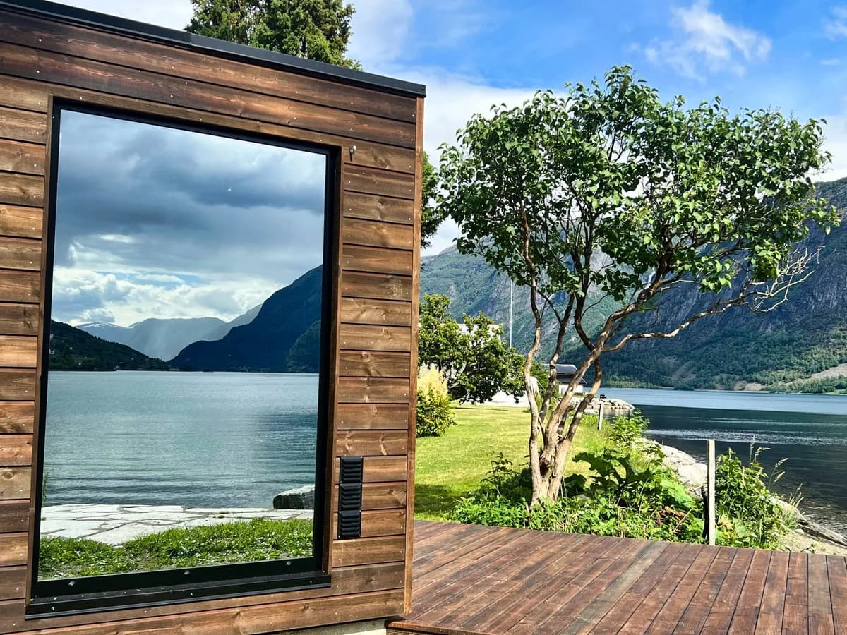 Fjordglimt Sauna i Luster sett utenfra med speilglass og utsikt mot Lustrafjorden og fjell