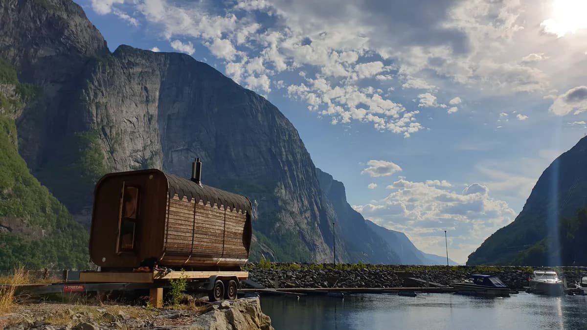 Vedfyrt tønnebastu ved fjorden hos SBK Base Sauna i Lysebotn med fjell i bakgrunnen