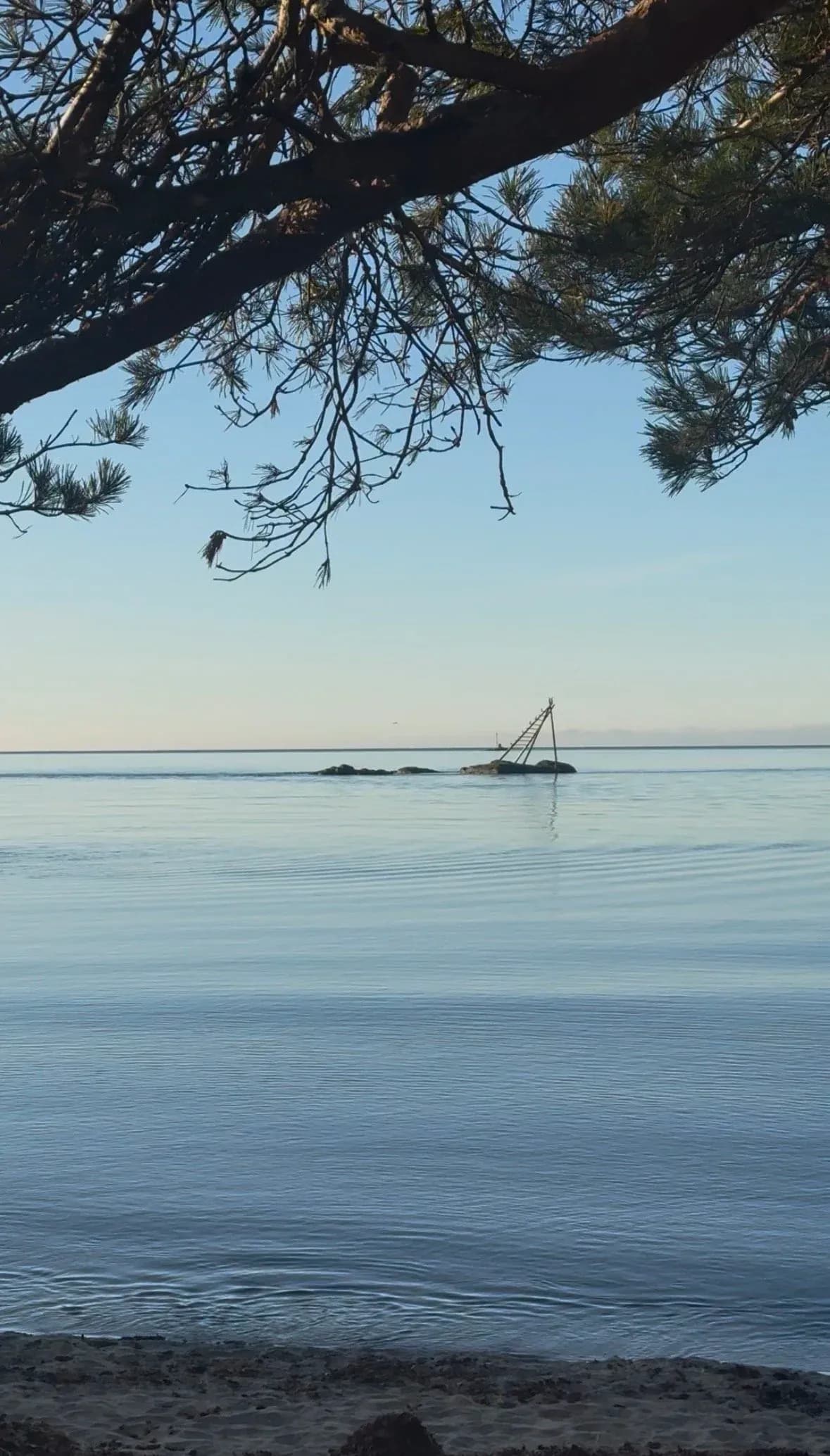 Utsikt mot havet fra stranden ved Piren/Sjøsanden, med et gammelt stupetårn på et skjær