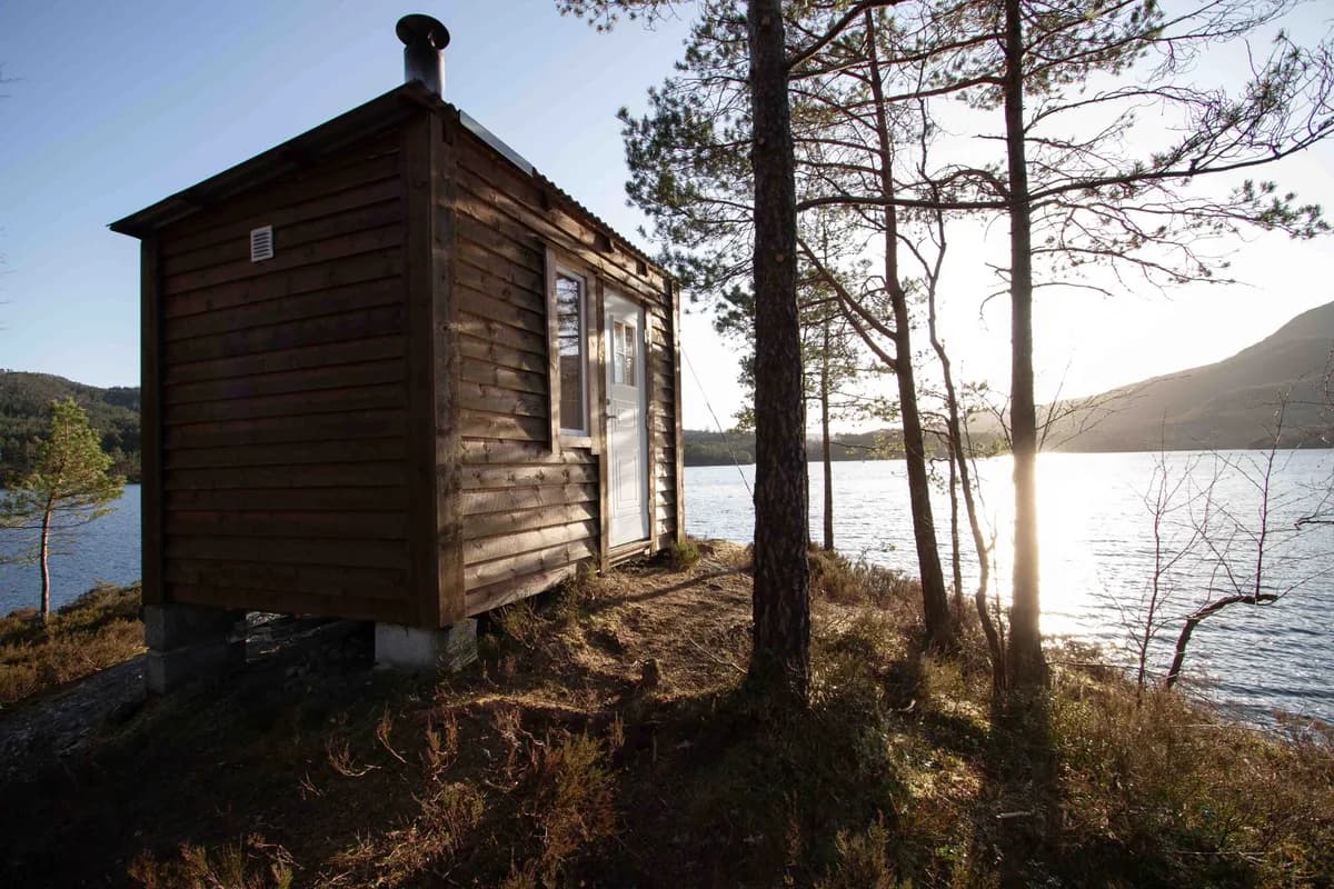 Torstveit Villmarksbadstu ved Stokkadalsvatnet i Nedre Vats, omgitt av furutrær i solnedgang