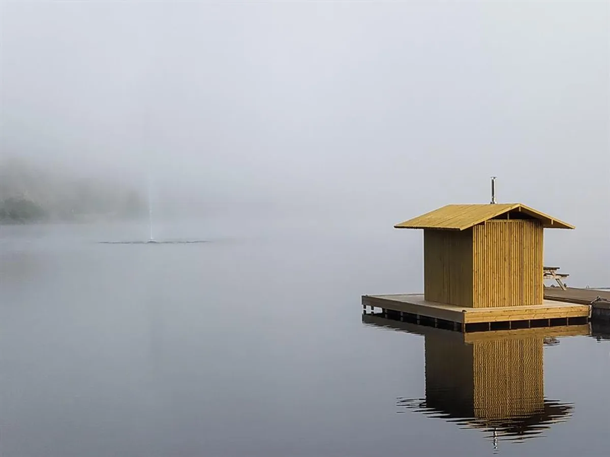 Flytende badstue Fyr Haldenkanalen på stille vann i tåke ved Ørje