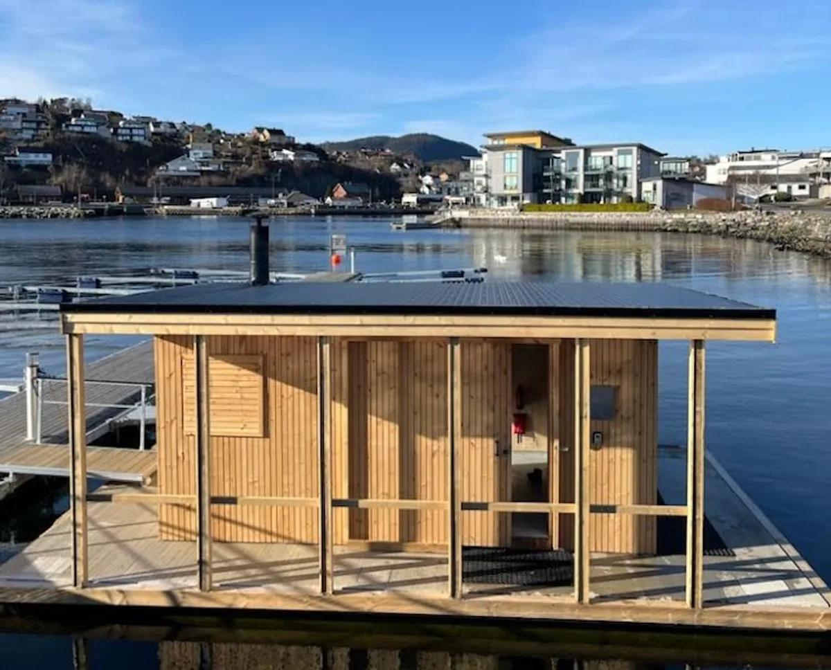 Os Sauna flytende badstue sett utenfra på Steinneset i Osøyro med fjorden og byen i bakgrunnen