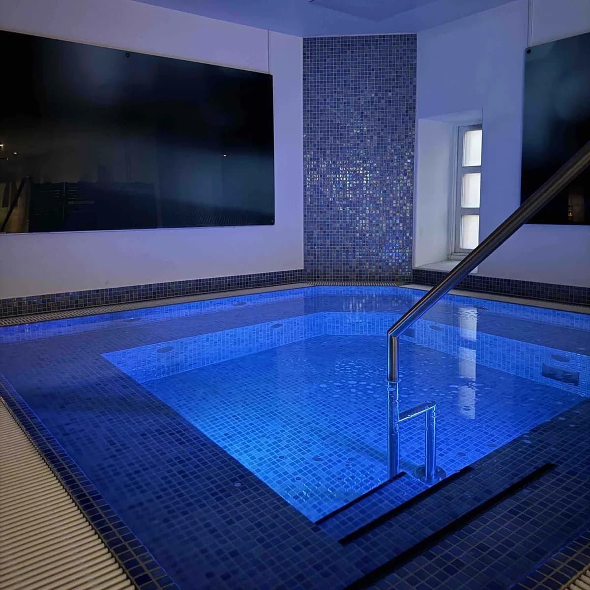 Jacuzzi med blå mosaikk og stemningsbelysning hos Bislet Bad & Trening i Oslo