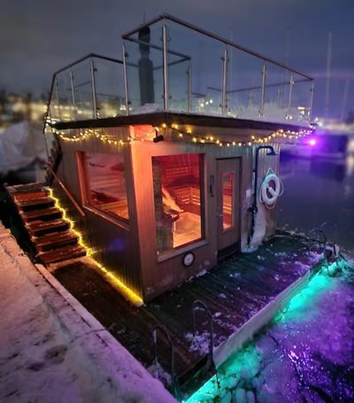 Flytende badstu Neptun fra Fjordtokt Båt & Badstu i Oslo, opplyst med lyslenker en vinterkveld