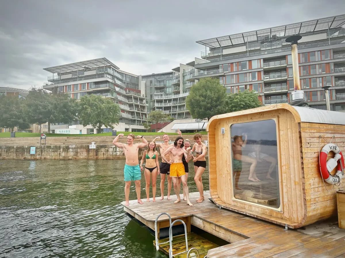 Mad Goats Tjuvholmen – gjester Gjester på flytebrygge ved den flytande badstua, med bygningar i bakgrunnen