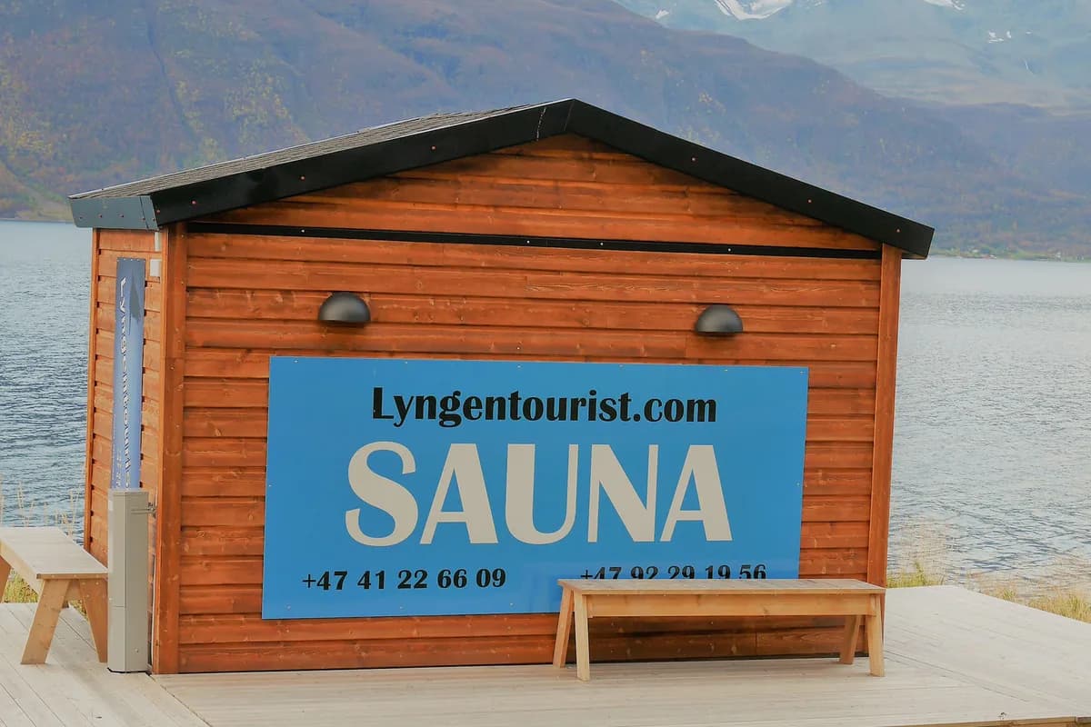 LyngenTourist Sauna i Oteren, trebygning med skilt ved Lyngenfjorden