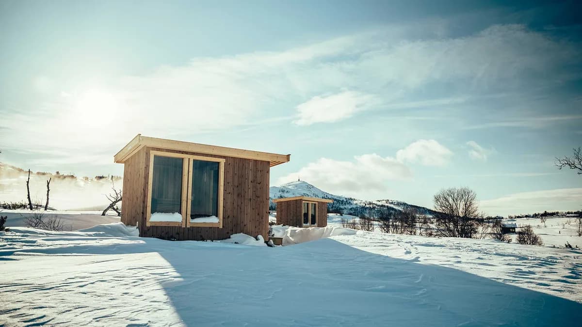 Vierli Badstuer i vinterlandskap ved Uvatn, Rauland, med snødekte fjell i bakgrunnen
