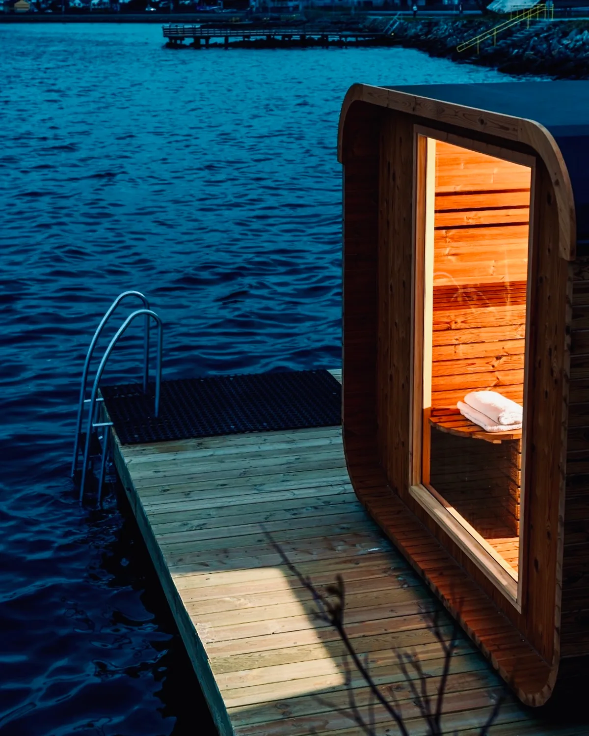 BookSauna Rikke flytende badstue på Gandsfjorden i Sandnes, opplyst innvendig ved kveldstid