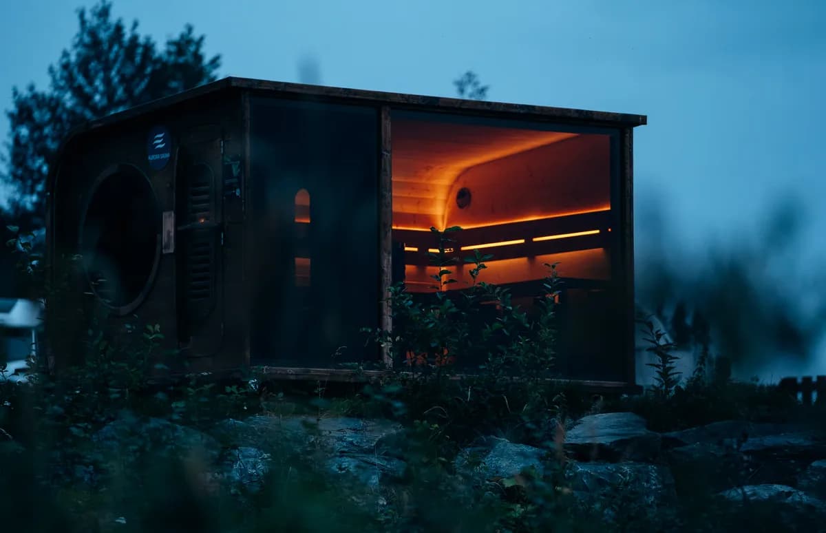 Aurora Sauna i Snåsa opplyst innenfra i kveldsmørke med varm belysning