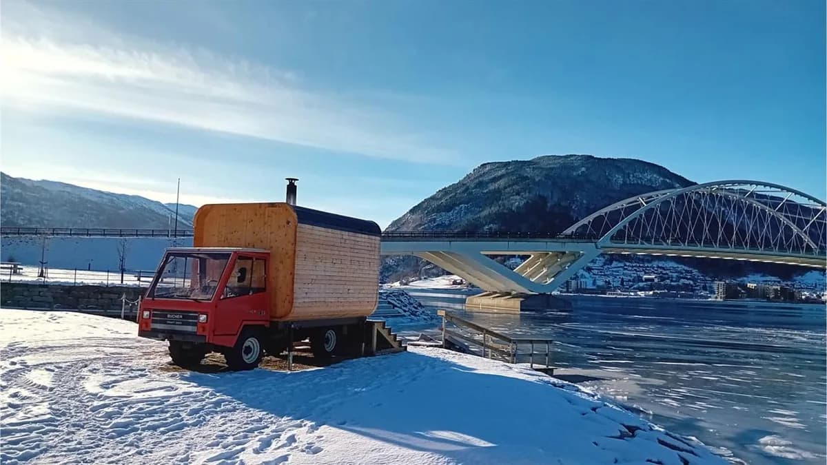 Heit Sogndal badstue på raud traktor ved Sognefjorden om vinteren med Loftesnes bru i bakgrunnen
