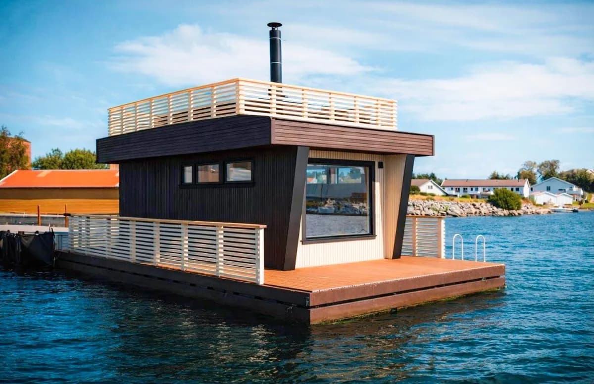 BookSauna Freja flytende badstu sett fra sjøen i Stavanger, med mørk trekledning, takterrasse og flytebrygge