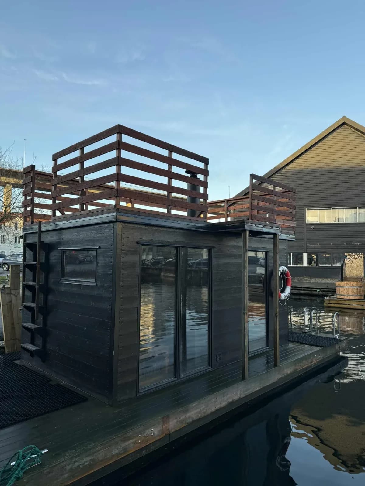 Flytende badstu Damp Helka i Svankevigå, Stavanger, med takterrasse og mørkt treverk