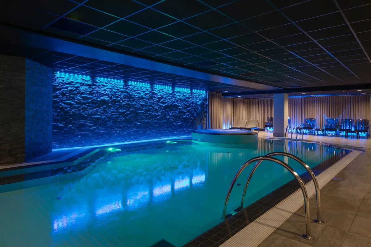 Innendørs basseng med blå belysning og steinvegg ved Scandic Royal Stavanger spa