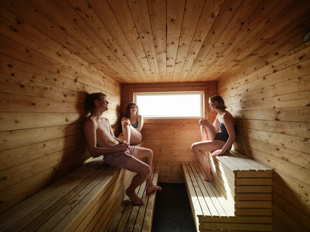 Interiør av vedfyrt badstu på Stokkøya Strandhotell med trebenker og havutsikt