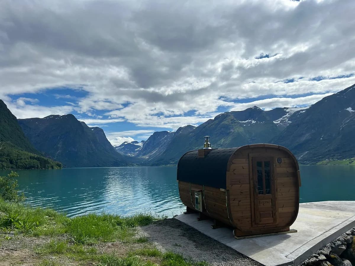 Tønnebadstu ved Oppstrynsvatnet med fjell og innsjø i bakgrunnen, Flo Brygge Sauna i Stryn