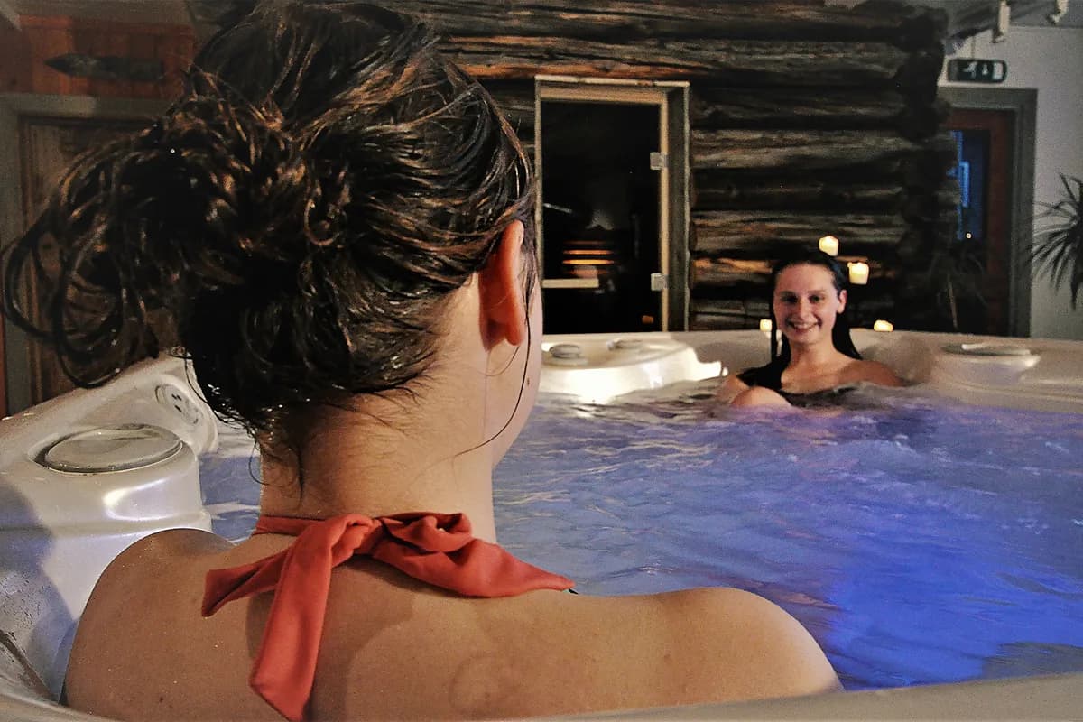 Gjester i jacuzzi ved Hindsæter Fjellspa i Tessanden, rustikk tømmervegg og levende lys