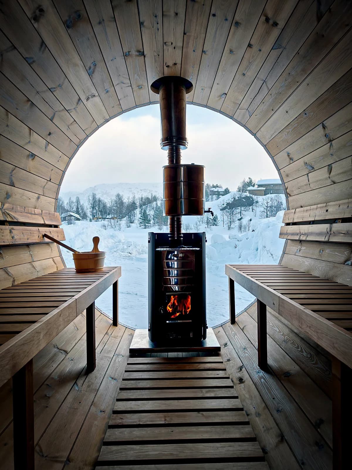 Interiør av Sauna Sirdal i Tjørhom med vedfyrt ovn og utsikt til snødekte fjell