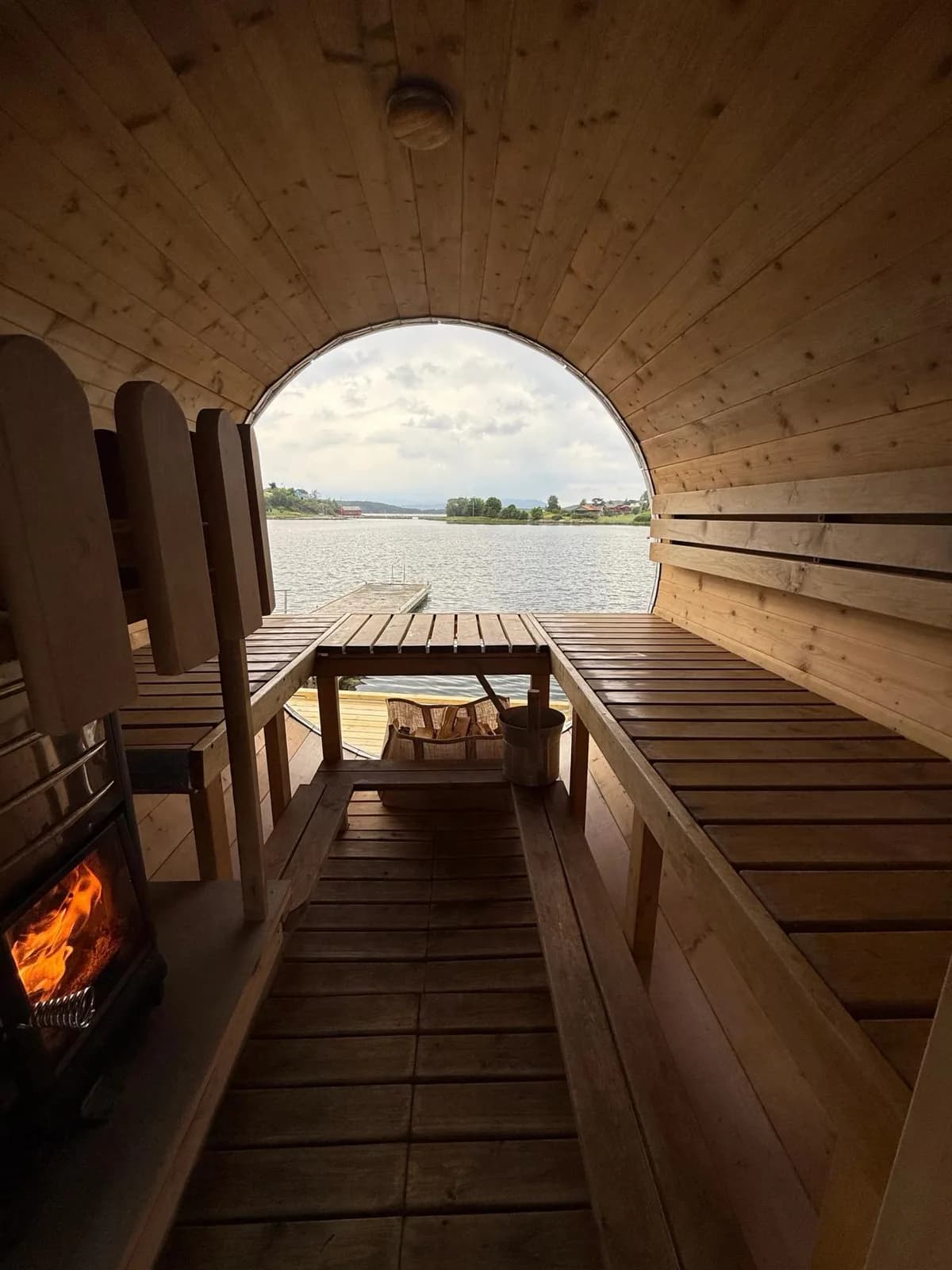 Innvendig i Badstova i Uskedalen med vedfyrt omn og utsikt mot fjorden gjennom boga opning