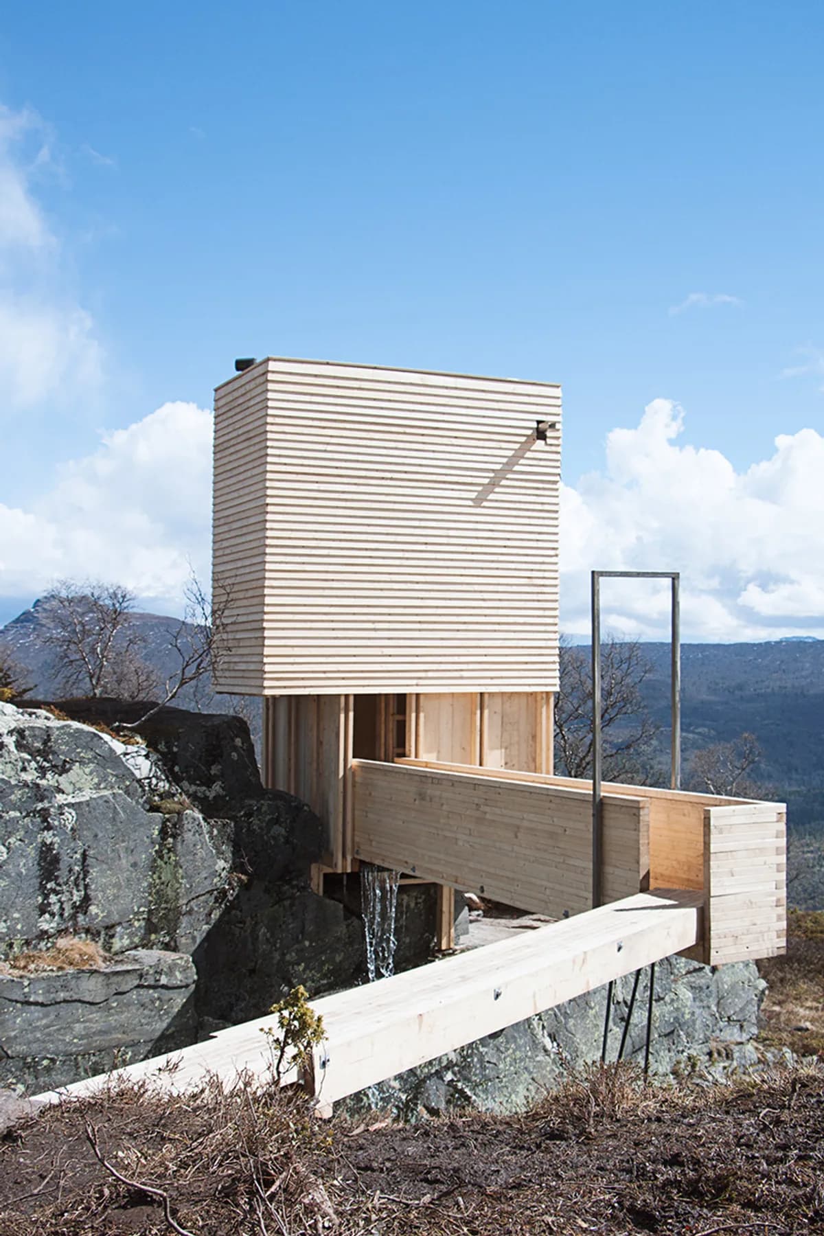 Eldmølla badstue i Vang i Valdres, svevende over fossefall med fjell i bakgrunnen